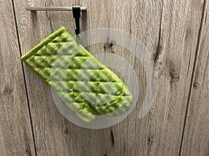 A green oven mitt hanging on a kitchen cabinet door