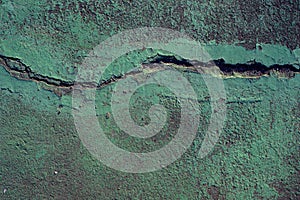 Green painted asphalt with earthquake crack photo. Cement floor stain and grit closeup. Urban texture