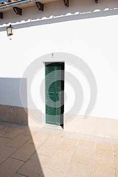 Green painted door in the sun with shadows