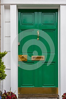 Green painted front door with white frame and brass furniture