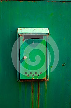 Green painted steel mail box on metal fence