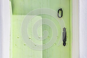 Green-painted vintage wooden door with metal handle close up