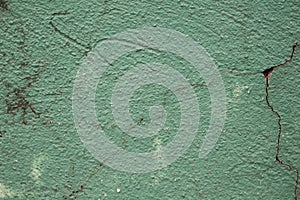 Green painted wall with cracks photo texture. Cement wall with stains and grit closeup.