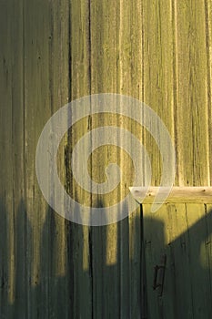 A green painted wooden wall with a small door