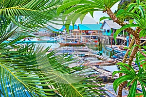 The green palm and plumeria leaves against Ko Panyi village, Phang Nga Bay, Thailand