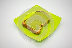Green pandan custard with coconut milk on toasted bread on green plastic plate isolated on white