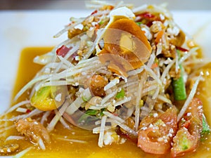 Green papaya salad or Som tum with preserved egg. Popular Thai local food. Spicy salad from shredded unripe papaya, sliced tomato