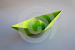 Green paper boat origami isolated on a grey background