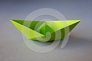 Green paper boat origami isolated on a grey background