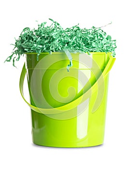 Green paper Easter grass in wooden bowl over white