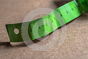 Green paper measuring meter on the brown cardboard, measure tape closeup