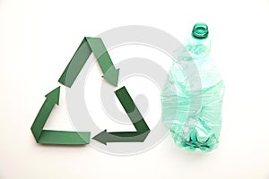 Green paper recycling symbol with empty plastic water bottles