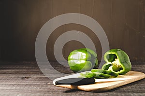 green paprika knifed white on a wooden board/ green paprika knifed white on a wooden board on a dark background with copy space