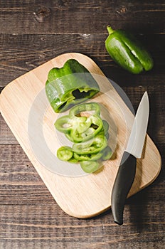 green paprika knifed white on a wooden board/green paprika knifed white on a wooden board on a dark background. Top view