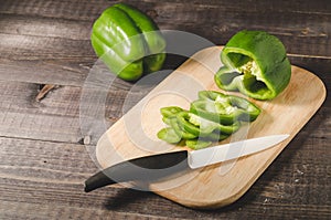 green paprika knifed white on a wooden board/green paprika knifed white on a wooden board and dark table