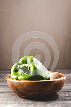 Green paprika on a wooden bowl/Green paprika pepper on a wooden