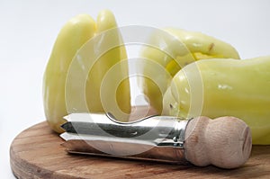 Green paprikas with cleaning tool on the wooden board