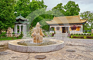 Green park with stone fountain and traditional chinese buddhist temple