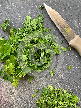 Green parsley on a board, sliced parsley, fresh vitamins, green plants, a small knife