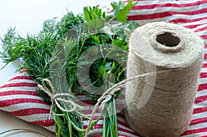 Green parsley and dill leaves on natural linen napkin on wooden background