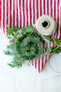 Green parsley and dill leaves on natural linen napkin on wooden background