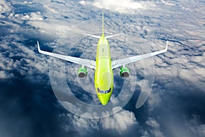 Green passenger plane fly over the clouds. Front view.