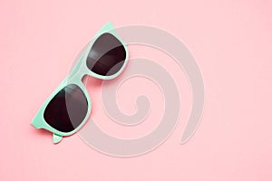 Green pastel sunglasses isolated on punchy pink, top view. Copy space. Summer concept.