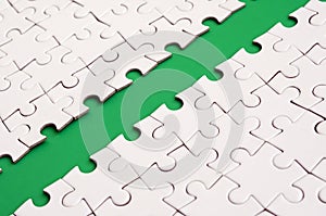 The green path is laid on the platform of a white folded jigsaw puzzle. Texture image with copy space for text