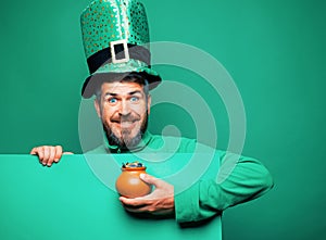 Green patricks background. Man in Patrick`s suit smiling. Man in Saint Patrick`s Day leprechaun party hat having fun on photo