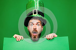 Green patricks background. Man in Saint Patrick's Day leprechaun party hat having fun on green background. Copy photo