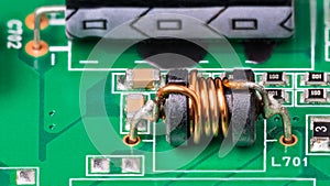 Green PCB detail with electromagnetic coil and electronic surface-mount components photo