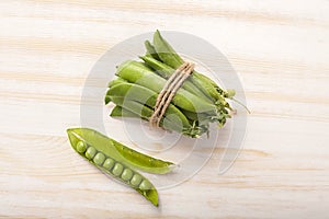 Green pea pod on wooden table