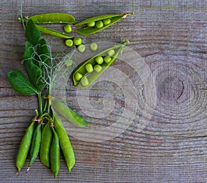 Green pea pods on old wooden surface close-up