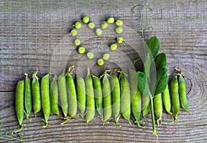 Green pea pods on old wooden surface close-up