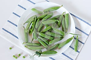 green pea pods on a plate, top view, flat layout.