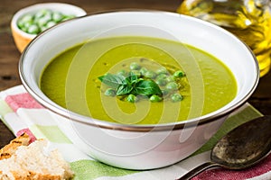 Green pea soup in bowl on wooden table