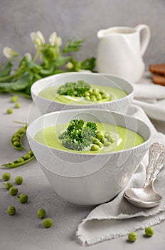 Green pea soup in bowls on grey concrete or stone background