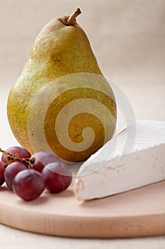 Green pear, cheese brie, red grapes on board