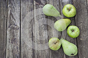 Green pears and apples with leafs on old, wooden table. High angle view