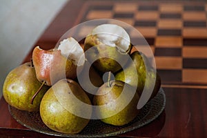 Green pears lie on plate next to chessboard