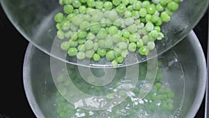 Green peas in bowl shift in water close-up