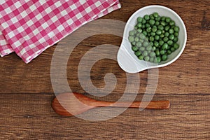 Green peas in a bowl on a wooden table