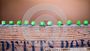 Green peas lined up on top of a retro wooden box with photo