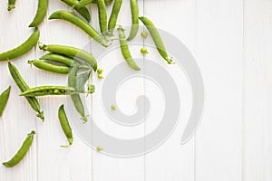 Green peas pods and seeds on white table top view.