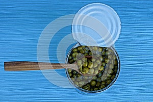 Green peas in a tin can and a wooden spoon