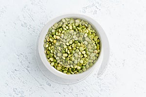Green peas in white bowl on white background. Dried cereals in cup, vegan food. Top view, close up