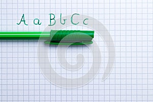 Green pen with handwritten letters on sheet of squared paper