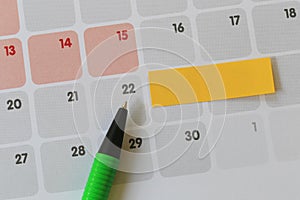 Green pen points to a Twenty-two number of calendar and have blank yellow note paper.