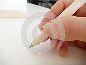 Green pencil in a hand writing