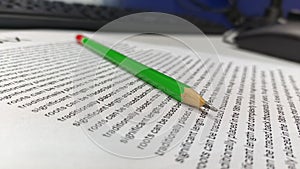 Green Pencil Resting on Text Document on Office Desk